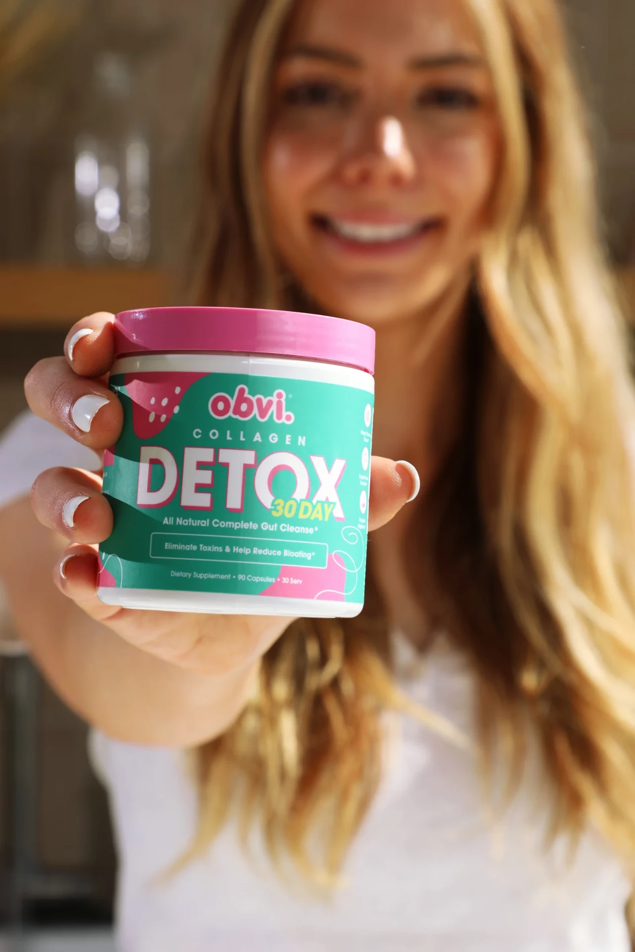Woman holding Obvi Collagen Detox toward the camera.